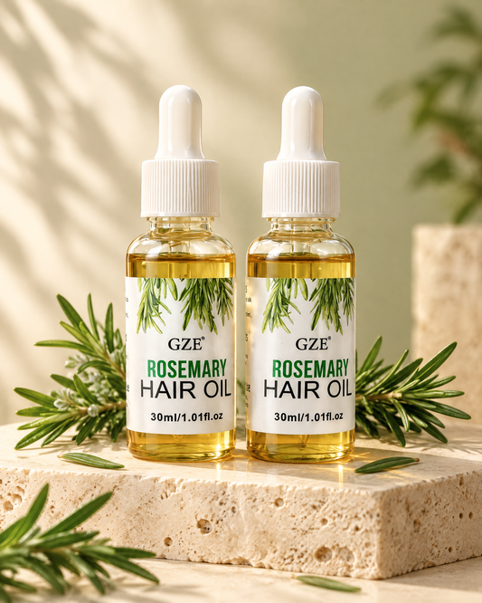 Two rosemary hair and scalp oil bottles on cream travertine with fresh rosemary